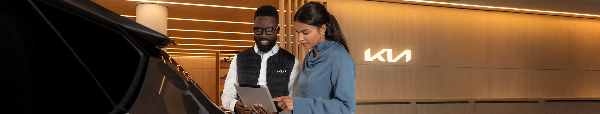 Servicemitarbeiter und Kundin mit Tablet am Fahrzeug